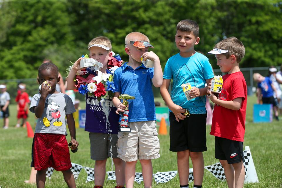 The winning team of Mayflowers Mill Elementary School's 5th annual Kindy 500, Rowdy Fast Racers: Xavier White, Timothy Griffin, Lincoln Blom, Bryson Hill and Charlie Thomas, begin to drinking their celebratory milk after being awarded the Kindy 500 throphy, on Monday, May 23, 2023, in Lafayette, Ind.