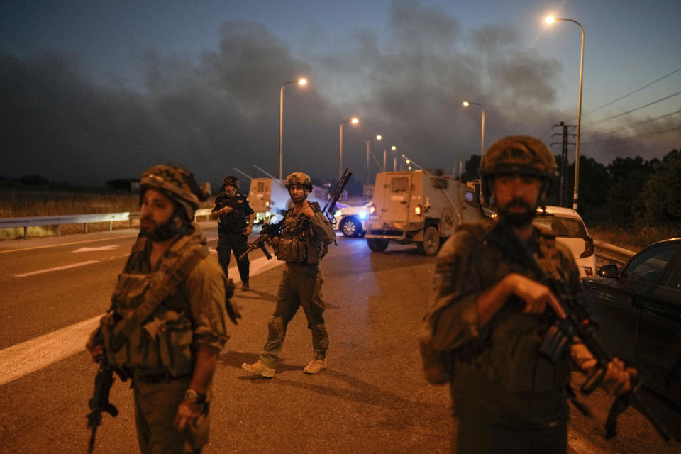 Israeli soldiers block a road backdropped by smoke from a fire after a rocket fired from Lebanon hit in the Israeli-annexed Golan Heights, Tuesday, July 9, 2024. (AP Photo/Leo Correa)