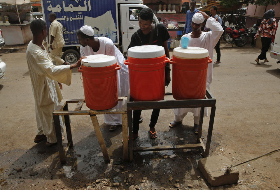 Sudanese drink water from a communal dispenser at a popular market, in Khartoum, Sudan, Monday, June 24, 2019. (AP Photo/Hussein Malla)