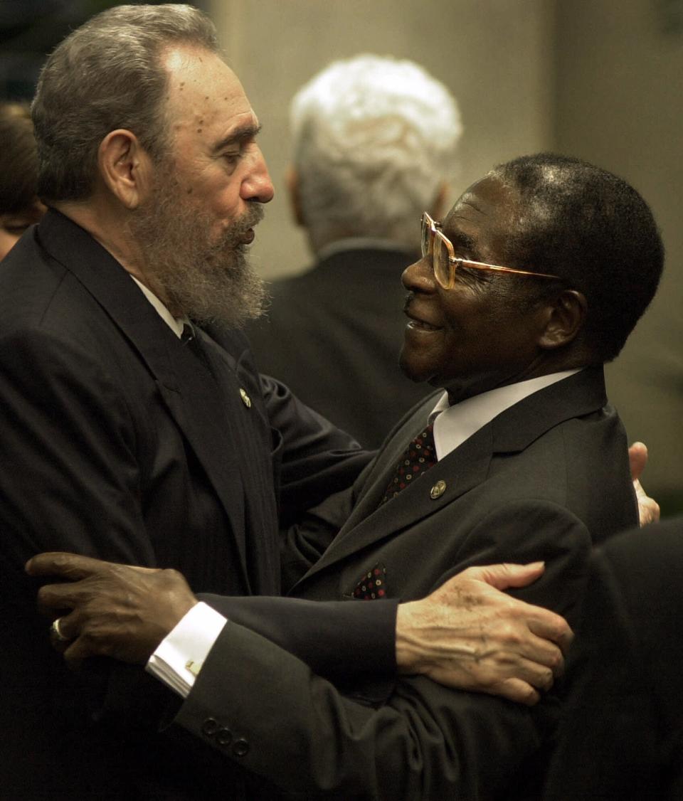 FILE - In this April 12, 2000 file photo, Cuba's leader Fidel Castro, left, greets Zimbabwe's President Robert Mugabe at a dinner reception during the South Summit of developing nations in Havana, Cuba. (AP Photo/Victor R. Caivano, File)