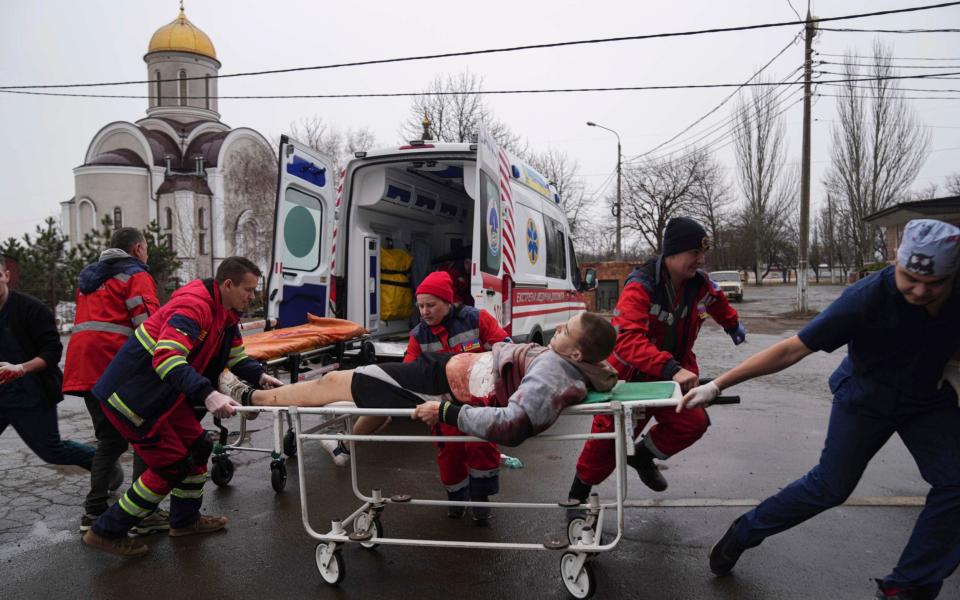 Ambulance paramedics wheel an injured man into a converted medical ward and bomb shelter in Mariupol - Evgeniy Maloletka /AP