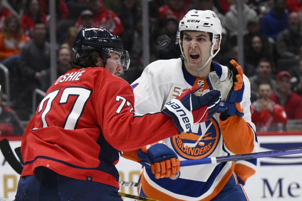 Washington Capitals right wing T.J. Oshie (77) and New York Islanders defenseman Samuel Bolduc (4) battle for the puck during the second period of an NHL hockey game, Wednesday, March 29, 2023, in Washington. (AP Photo/Nick Wass)