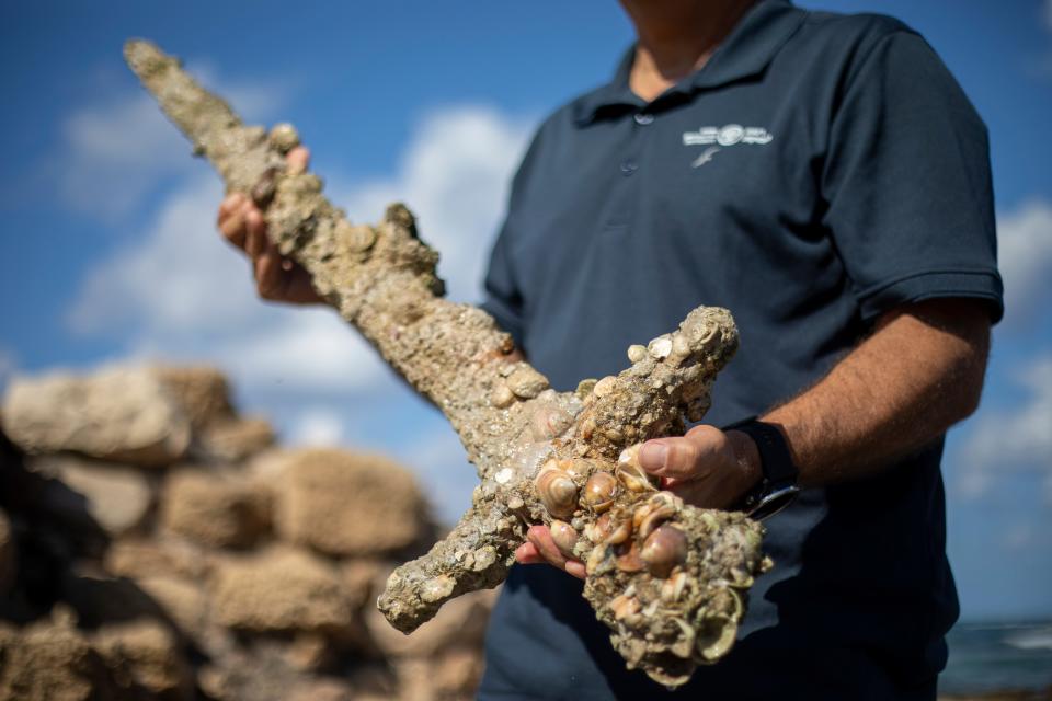 Jacob Sharvit, director of the Marine Archaeology Unit of the Israel Antiquities Authority holds a yard-long sword, one that experts say dates back to the Crusaders, that is on display in the Mediterranean seaport of Cesarea, Israel. Israel's Antiquities Authority said on Oct. 18, 2021, that a scuba diver was on a weekend dive in northern Israel over the weekend when he spotted a trove of ancient artifacts that included anchors, pottery and the sword.