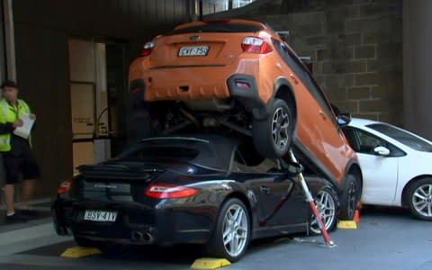 A valet drove the soft-top Porsche Carrera under another vehicle Thursday outside the Hyatt Regency Hotel in Sydney - Credit: AP