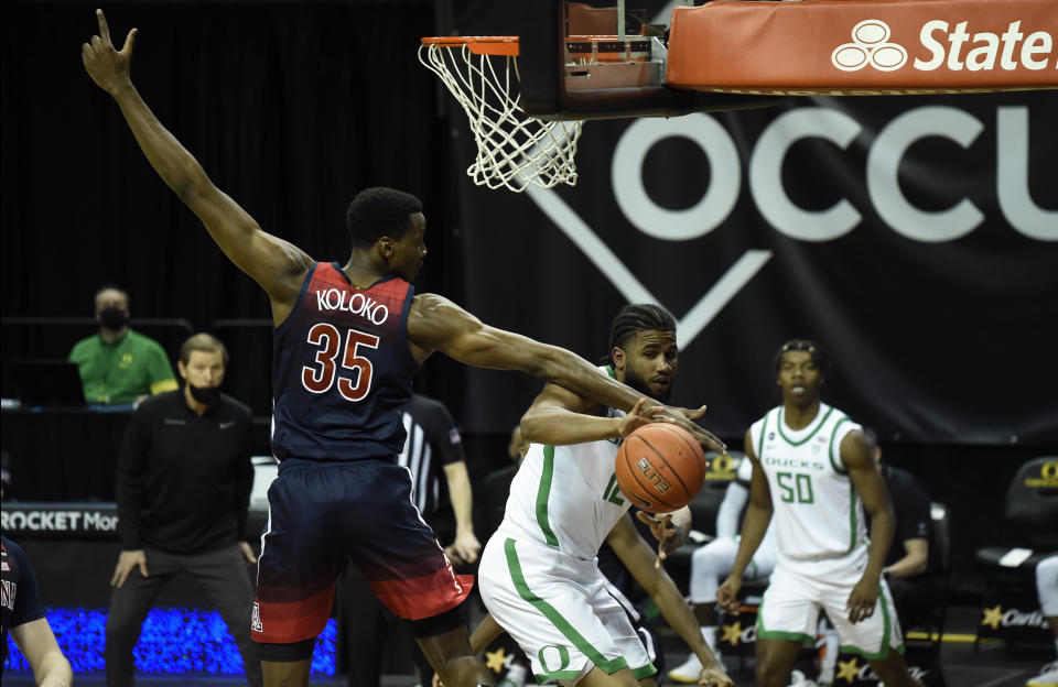 Arizona center Christian Koloko (35) tries to block the pass of Oregon guard LJ Figueroa (12) during the second half of an NCAA college basketball game Monday, March 1, 2021, in Eugene, Ore. (AP Photo/Andy Nelson)