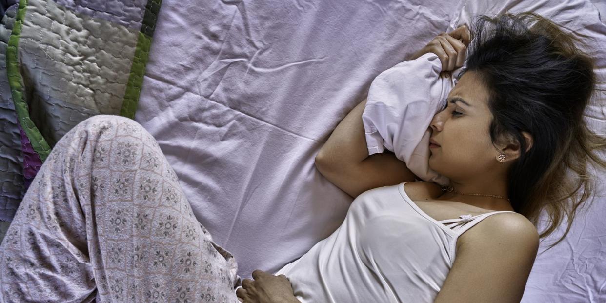hispanic young woman suffering pms pain in bed