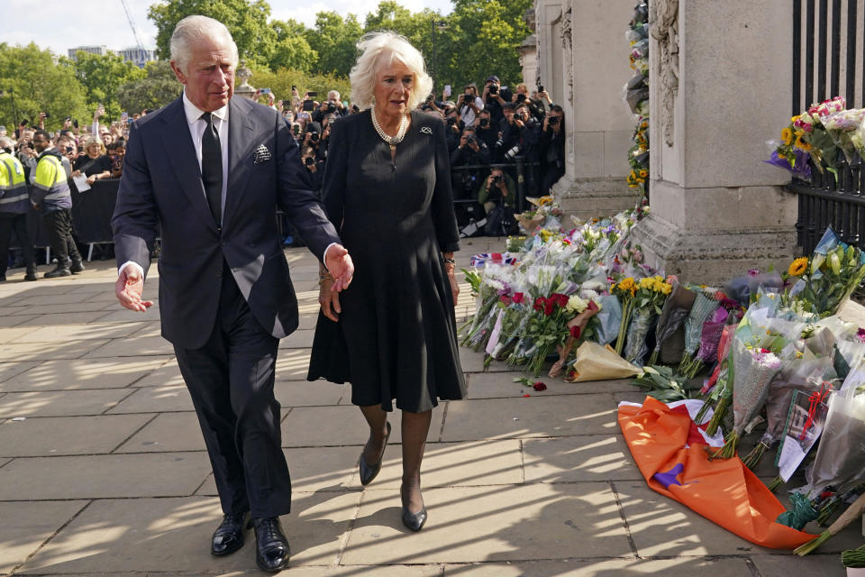 Britain's King Charles III, left, and Camilla, the Queen Consort, look at floral tributes outside Buckingham Palace following Thursday's death of Queen Elizabeth II, in London, Friday, Sept. 9, 2022. King Charles III, who spent much of his 73 years preparing for the role, planned to meet with the prime minister and address a nation grieving the only British monarch most of the world had known. He takes the throne in an era of uncertainty for both his country and the monarchy itself. (Yui Mok/Pool Photo via AP)