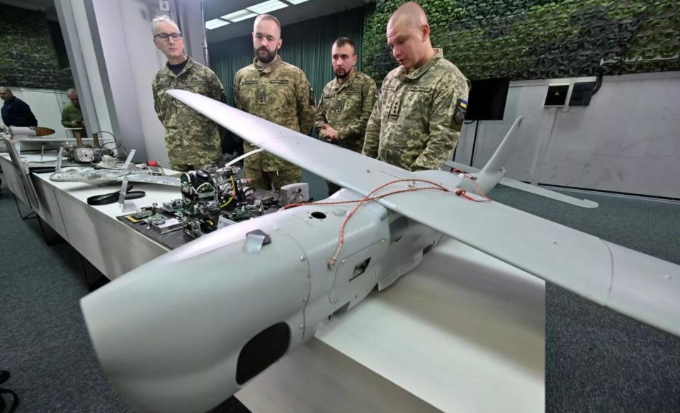 Ukrainian military personnel display a downed Russian drone during a press conference.