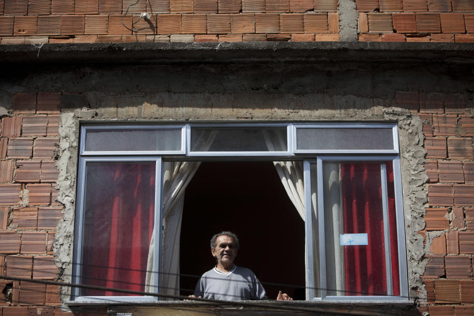 In this May 10, 2012 photo, Jose Nazare Braga looks out from his home in the Rocinha shantytown in Rio de Janeiro, Brazil. The building is Braga's nest egg, his retirement home and an inheritance for his large family. But for decades, the property wasn't formally his, and he lived in far he might lose it all. Now local officials and human rights groups are working to give legal title to tens of thousands of people like Braga, a process that increases their wealth and gives them greater access to credit, as well as peace of mind. (AP Photo/Felipe Dana)