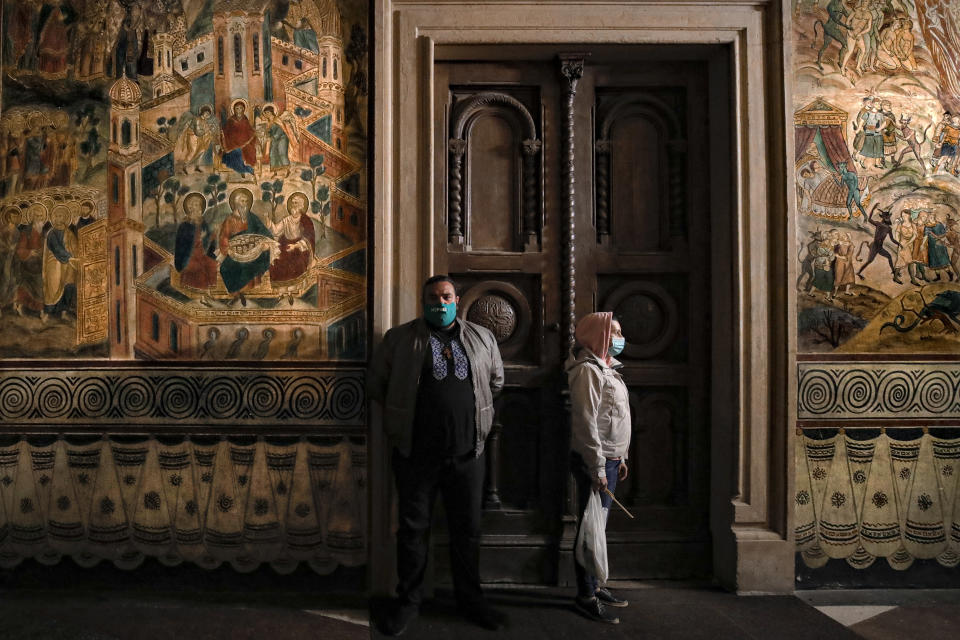 Orthodox worshipers, wearing masks for protection against the COVID-19 virus, wait for a religious service in the Black Sea port of Constanta, Romania, late Tuesday, May 26, 2020. (AP Photo/Vadim Ghirda)