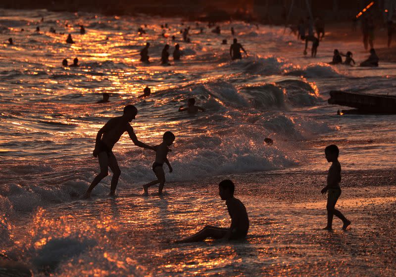 People enjoy the sea during sunset in Yevpatoriya