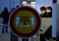 Employees wearing face masks look past a sign promoting safe distancing measures, as Skoda Auto restarts production at its factory following a shutdown last month due to the coronavirus disease (COVID-19) outbreak in Mlada Boleslav