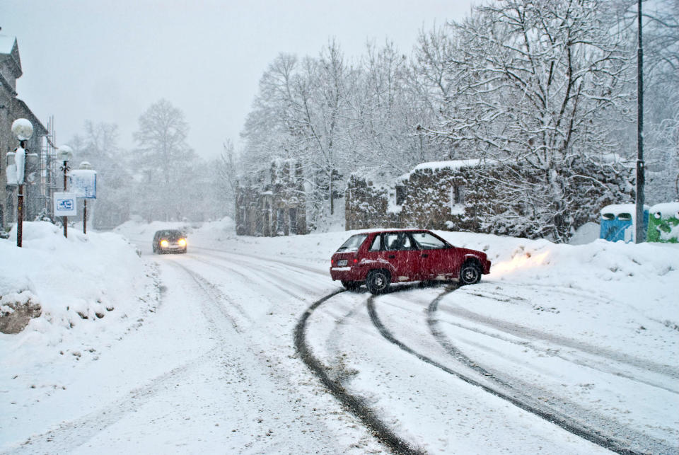 Cars driving in the snow with one stalled on the side of the road