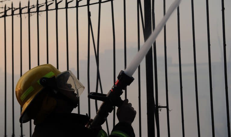 A firefighter extinguishes a fire in Quezon City, east of the Philippine capital of Manila on April 19, 2012. Three American men and a South Korean were among seven people who died on Friday when a fire razed a hotel in a red-light district near a former US naval base in the Philippines, authorities said