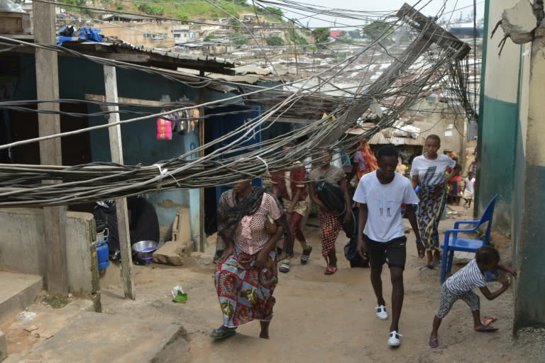 Los habitantes de un distrito de Abiyán caminan entre los cables de tendido eléctrico el 1 de junio de 2019 (Sia Kambou)