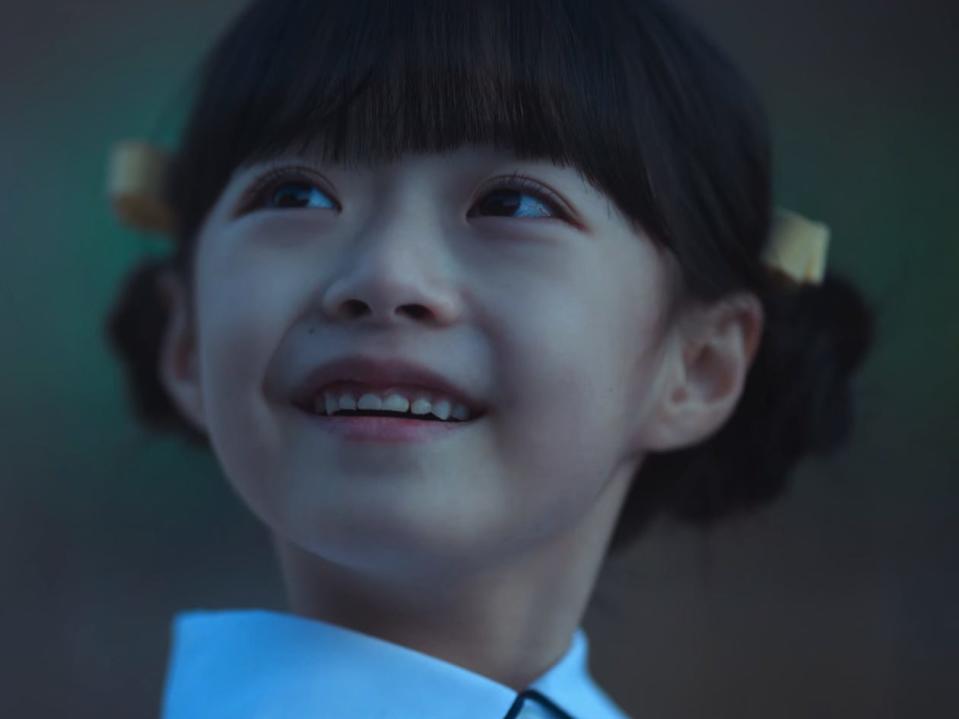 ha ye-sol in the glory. she is a young child with her styled in two ponytails and yellow bows, smiling widely up at another person