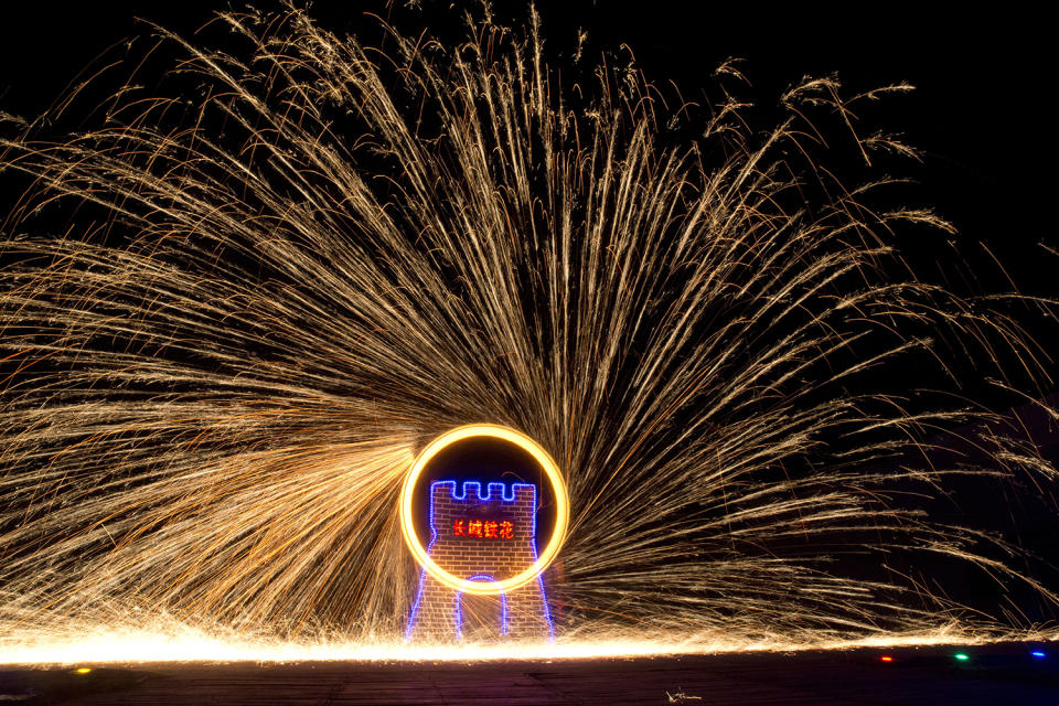 Performers turn a wheel spinning molten iron to create sparks at the Great Wall Iron Sparks show in Yanqing county on the outskirts of Beijing, China, Saturday, Jan. 28, 2017. An ancient craft that can be traced back several hundred years, the company is trying to revive the practice of throwing the molten iron and using the Lunar New Year period to showcase their latest choreography. Chinese character in center reads 