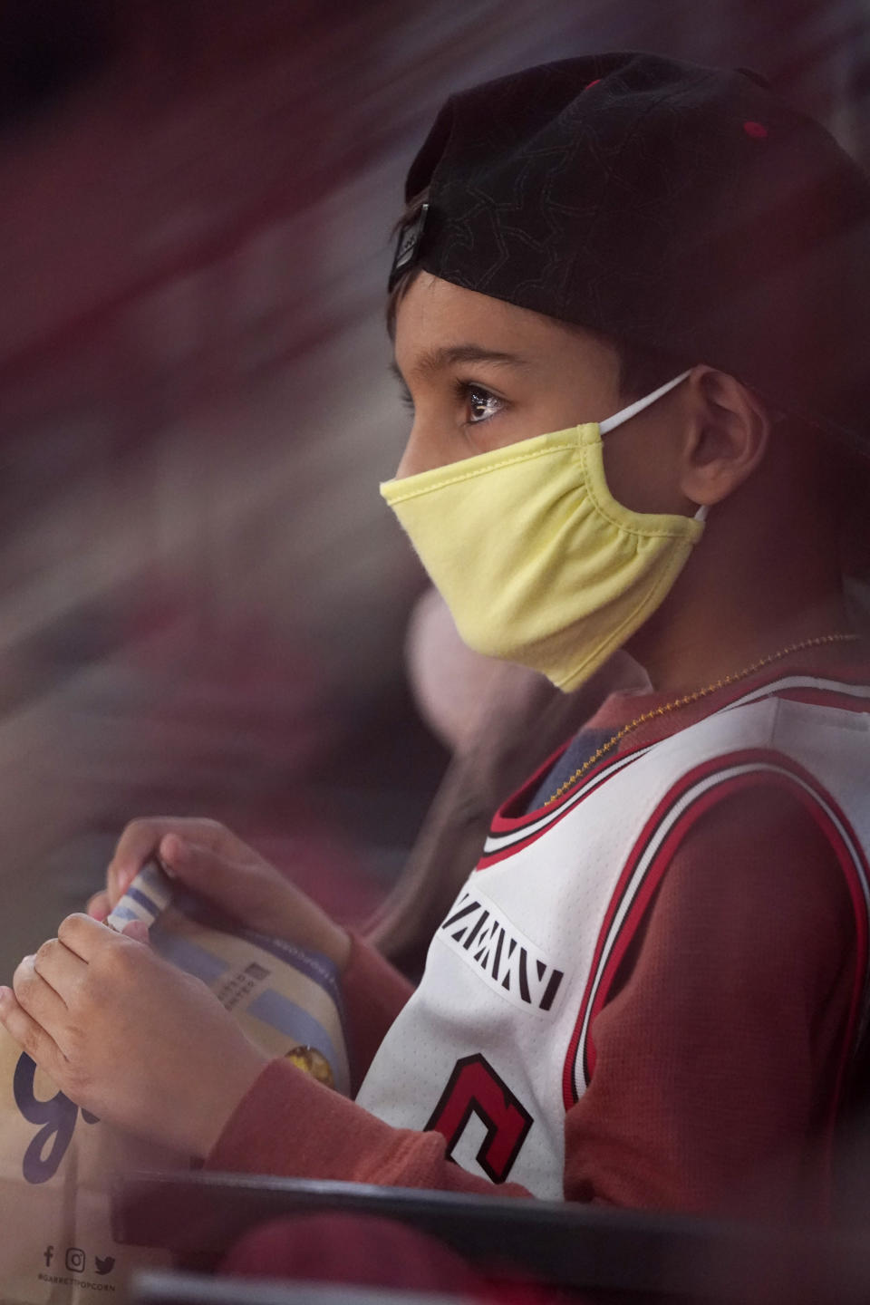 Jaxen Desai, 7, wears mask as he watches the first half of an NBA basketball game between the Boston Celtics and the Chicago Bulls in Chicago, Friday, May 7, 2021. (AP Photo/Nam Y. Huh)