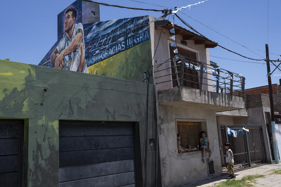 Children gather under a mural of soccer player Lionel Messi that covers the home where he lived in Rosario, Argentina, Wednesday, Dec. 14, 2022. (AP Photo/Rodrigo Abd)