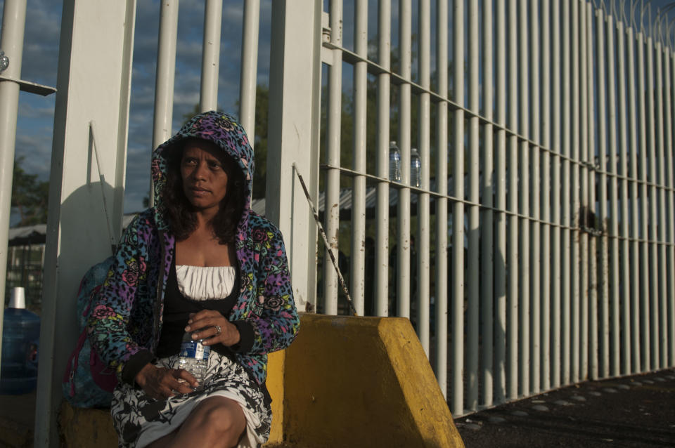 La migrante hondureña Gloria Emilia Mejía, de 38 años, espera ser atendida por las autoridades migratorias mexicanas junto a la reja que divide a Guatemala y México en Tecún Umán, Guatemala, la mañana del domingo 21 de octubre de 2018. (AP Foto/Oliver de Ros)