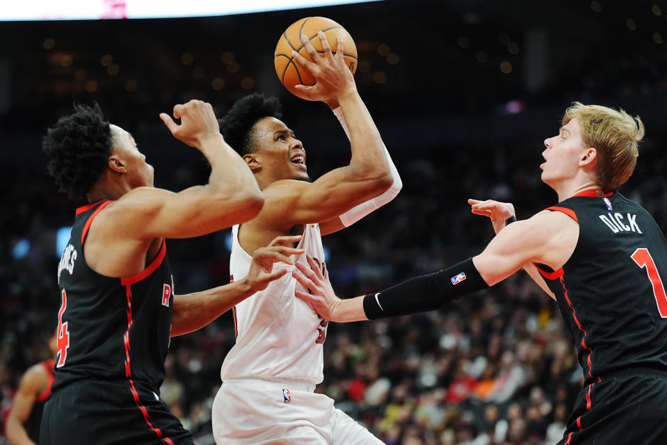 Cleveland Cavaliers forward Isaac Okoro (35) shoots between Toronto Raptors forward Scottie Barnes (4) and guard Gradey Dick (1) during the second half of an NBA basketball game, Saturday, Feb. 10, 2024 in Toronto. (Frank Gunn/The Canadian Press via AP)