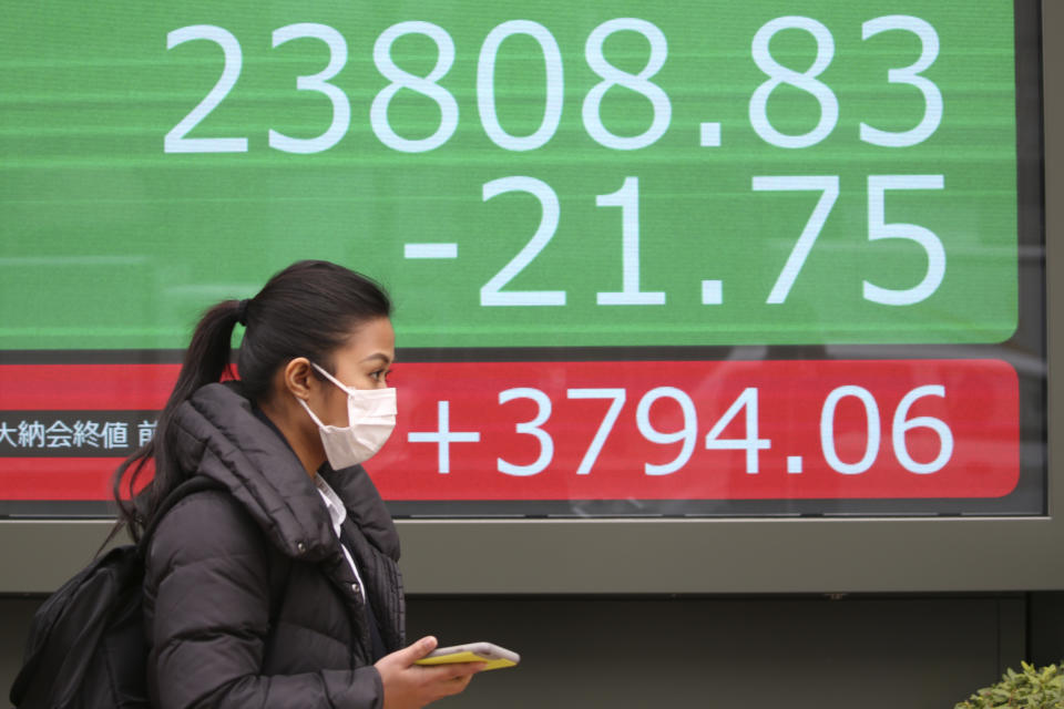 A woman walks by an electronic stock board of a securities firm in Tokyo, Wednesday, Dec. 25, 2019. Chinese and Japanese stocks declined Wednesday while most other Asian markets were closed for Christmas Day. (AP Photo/Koji Sasahara)