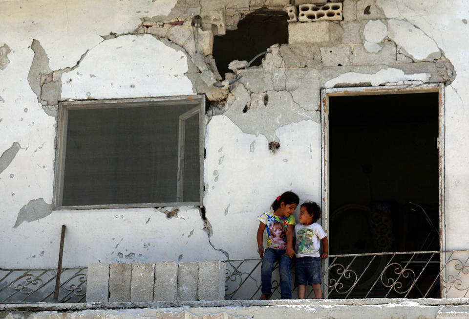 Children are seen at a damaged house in Deraa