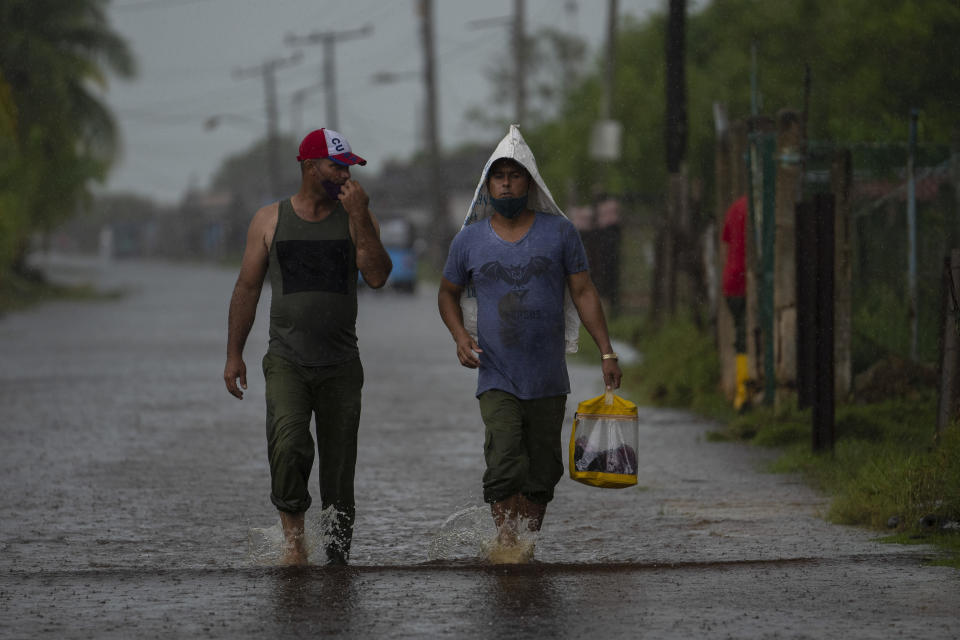 People walk down a street flooded by the rains brought on by Hurricane Ida, in Guanimar, Artemisa province, Cuba, Saturday, Aug. 28, 2021. (AP Photo/Ramon Espinosa)