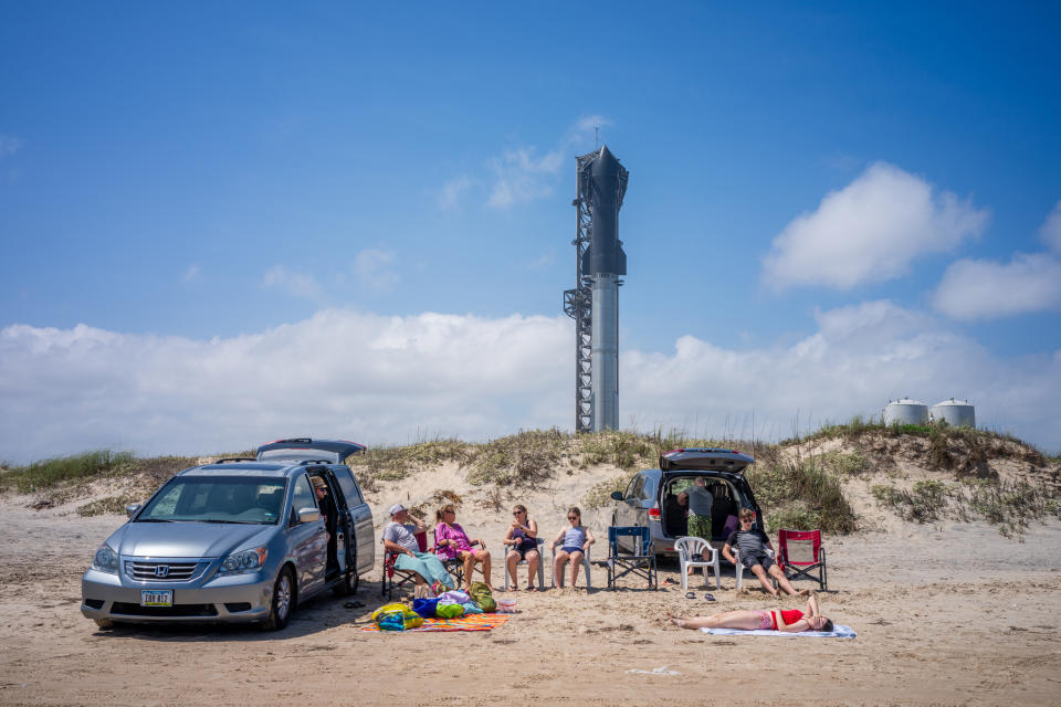 İnsanlar, planlanan fırlatılışından bir gün önce Teksas'taki sahilde Starship roketinin yakınında vakit geçiriyor.