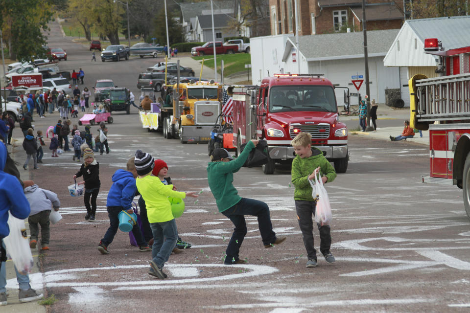 Children scramble for candy during a homecoming parade on Friday Oct. 16, 2020, in Wessington Springs, S.D. The parade had to be postponed due to a coronavirus outbreak that killed five residents of the local nursing home. (AP Photo/Stephen Groves)