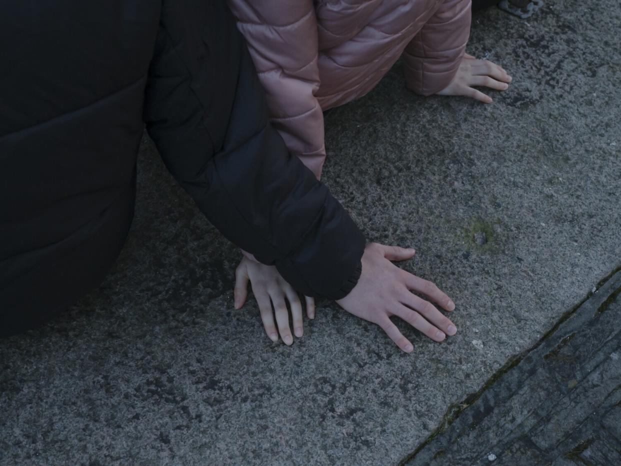 Hands rest on a concrete ledge