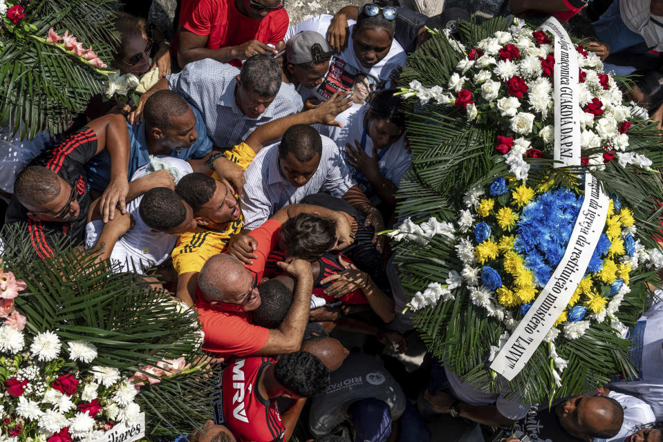 Friends and relatives of the late Christian Esmerio Candido embrace during his burial at a cemetery in Rio de Janeiro, Brazil, Sunday, Feb. 10, 2019. Hundreds of grief-stricken people attended the funeral of the 15-year-old, one or 10 young soccer players killed in a fire at the training ground of Brazilian soccer club Flamengo on Friday. (AP Photo/C.H. Gardiner)