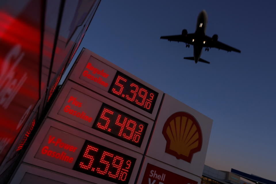 An aircraft flies over a sign displaying current gas prices as it approaches to land in San Diego, California, U.S., February 28, 2022.    REUTERS/Mike Blake