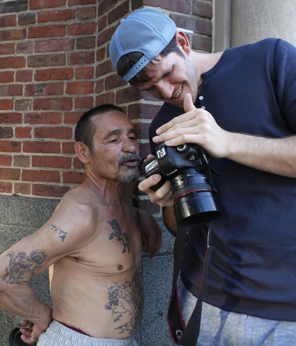 This Oct. 2, 2013 photo shows photographer Brandon Stanton, right, creator of the Humans of New York blog, showing Luis Torres, 63, a portrait he just took while combing the streets for subjects for his daily blog posts in New York. Stanton’s magical blend of portraits and poignant, pithy storytelling has earned HONY more than 2 million followers online. Now he’s putting his work in a book, “Humans of New York,” due out Oct. 15 from St. Martin’s Press. (AP Photo/Kathy Willens)