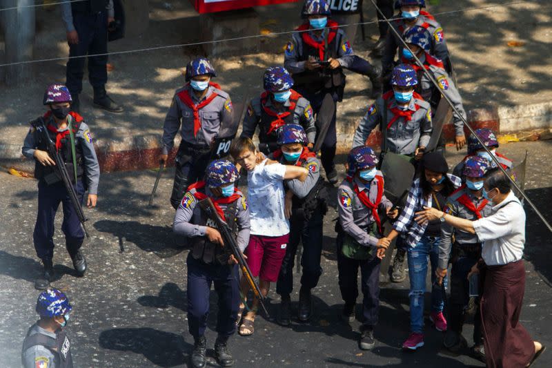 Pro-democracy protesters are detained by riot police officers during a rally against the military coup in Yangon