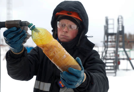 An employee takes a sample of crude oil for further analysis at a well head in the Yarakta Oil Field, owned by Irkutsk Oil Company (INK), in Irkutsk Region, Russia March 10, 2019. REUTERS/Vasily Fedosenko