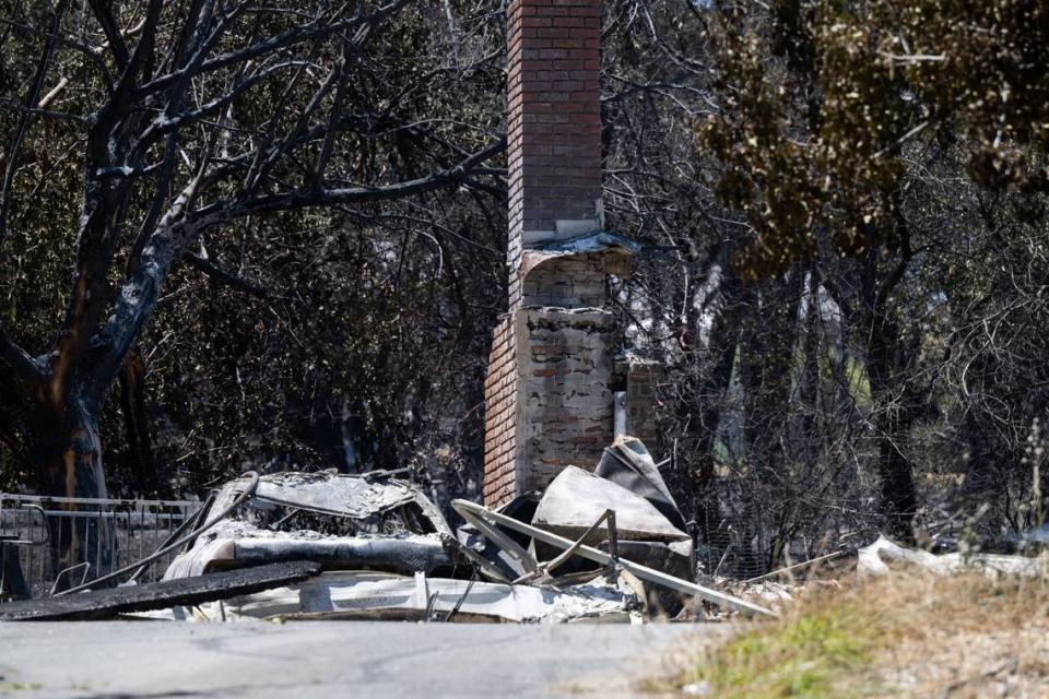 A burned down home and a vehicle from the Thompson Fire on is seen on Bessie Lane on Wednesday in Oroville.