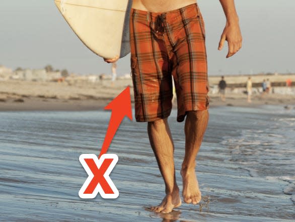 Young surfer holding a surfboard at the beach.