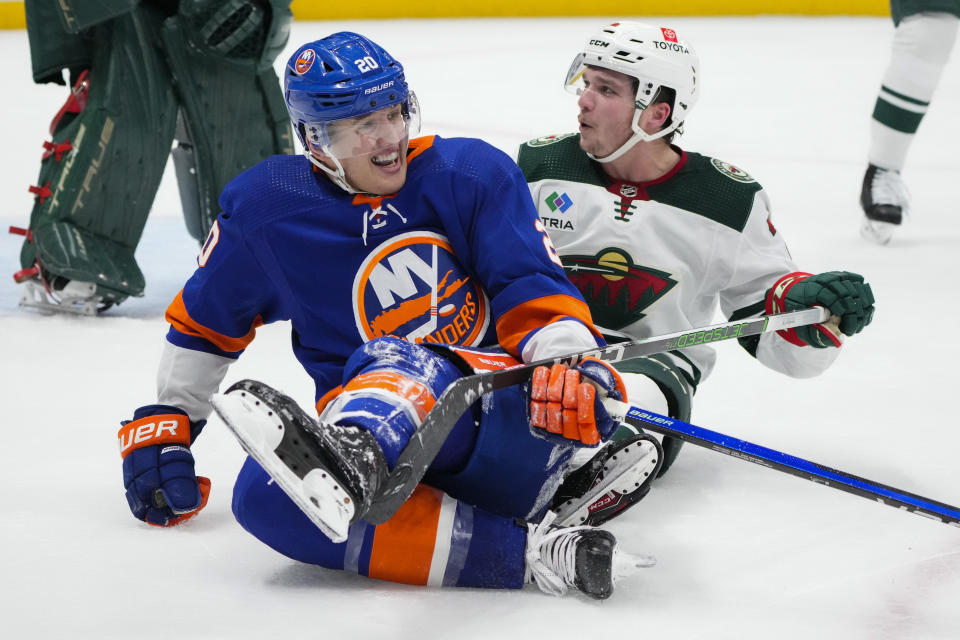 New York Islanders' Hudson Fasching (20) falls down with Minnesota Wild's Calen Addison (2) as they fight for position during the second period of an NHL hockey game Tuesday, Nov. 7, 2023, in Elmont, N.Y. (AP Photo/Frank Franklin II)