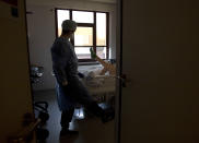 A physiotherapist from the Belgian Army works to exercise a patient with COVID-19 at the St. Michiel Hospital in Brussels, Tuesday, Nov. 24, 2020. The Belgian military has been called into several hospitals and care homes to alleviate the stress on healthcare personnel. (AP Photo/Virginia Mayo)