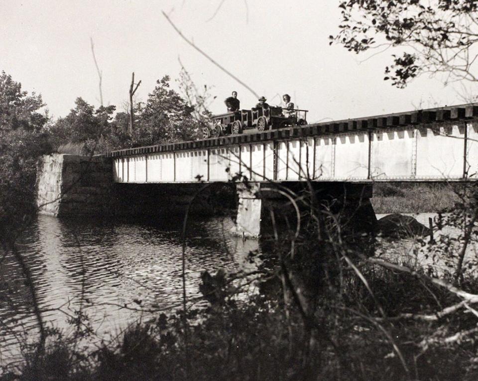 In 1947, patrons take a last ride across the Wood River on the final run of the Wood River Branch Railroad. The stone support pillars are still standing today, although the decking is gone.