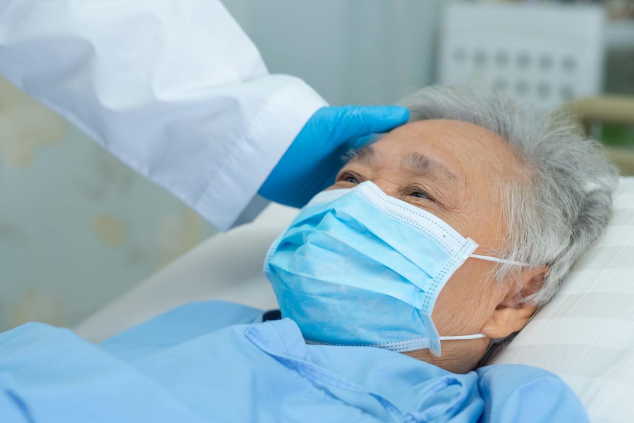 Doctor touching and checking Asian senior or elderly old lady woman patient wearing a face mask in hospital 