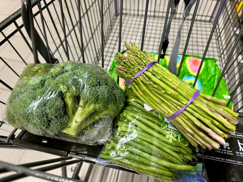 Broccoli, asparagus, and green beans in a black shopping cart at Aldi