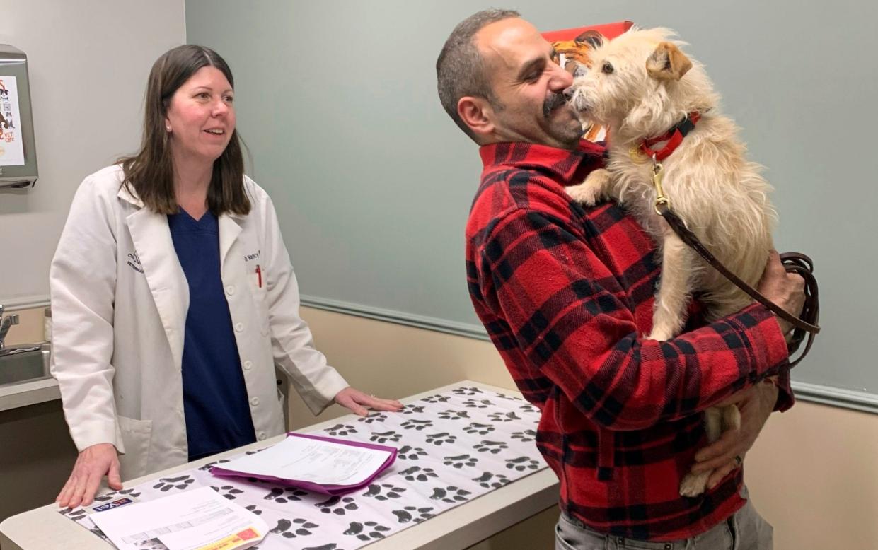 Mehrad Houman holds his dog, Mishka, after she was examined by veterinarian Nancy Pillsbury in Harper Woods, Michigan