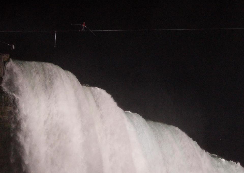 Nik Wallenda walks across Niagara Falls on a tightrope as seen from Niagara Falls, N.Y., Friday, June 15, 2012. Wallenda has finished his attempt to become the first person to walk on a tightrope 1,800 feet across the mist-fogged brink of roaring Niagara Falls. The seventh-generation member of the famed Flying Wallendas had long dreamed of pulling off the stunt, never before attempted. (AP Photo/James P. McCoy)