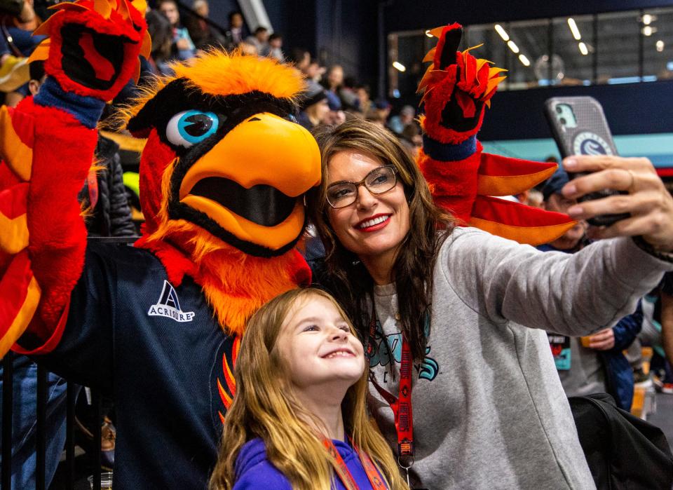 Caroline Brabrook and her daughter Alexa, 8, take a selfie with Fuego, the Coachella Valley Firebirds mascot, during the third period of their game at Kraken Community Iceplex in Seattle, Wash., Friday, Oct. 21, 2022. 