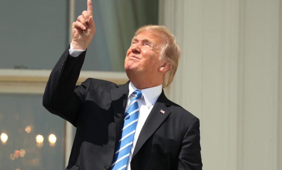 President Donald Trump points to the sun during the solar eclipse, Monday, Aug. 21, 2017, at the White House in Washington.