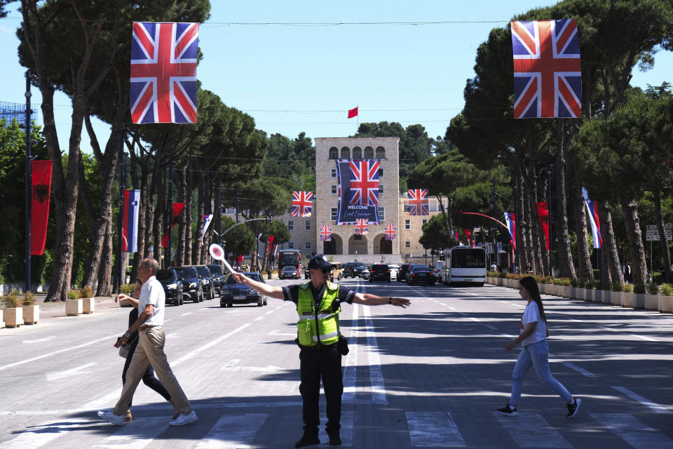 Pedestrians cross an avenue as British flags are hanged over the street in Tirana University, Albania, Wednesday, May 22, 2024. British Foreign Secretary David Cameron has hailed progress in a U.K.-Albania joint effort to cut illegal migration, saying small boat arrivals from Albania to the U.K. fell by over 90% in 2023, as the two countries fought people smuggling gangs. (AP Photo/Vlasov Sulaj)