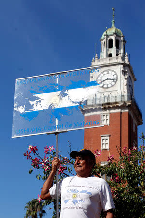 Miguel Condori, a demonstrator in a rally to support former Argentine President Cristina Fernandez de Kirchner, holds a banner with an image of the Falkland Islands, known in Argentina as Islas Malvinas, in front of the English Tower, a British monument donated to Argentina, in Buenos Aires, Argentina, March 7, 2017. Picture taken March 7. REUTERS/Martin Acosta