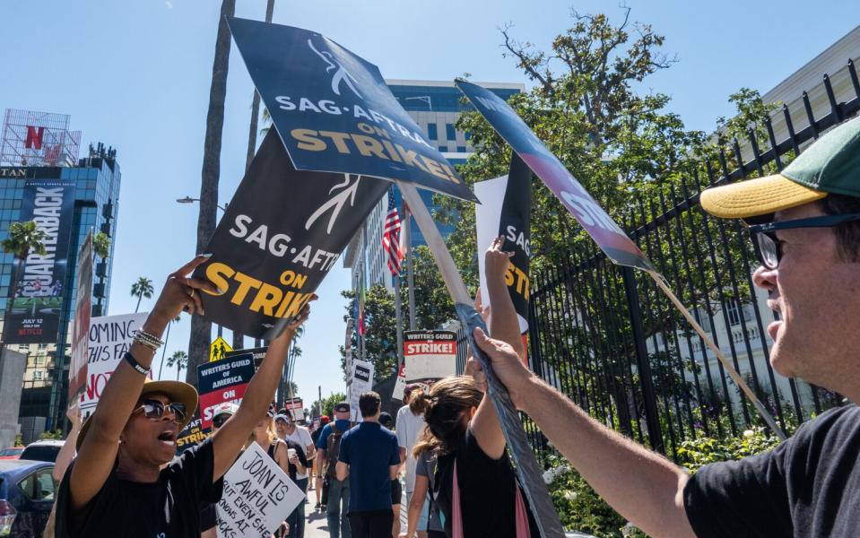 SAG-AFTRA member Bennie Arthur, right, taps signs with picketers at the end of the line